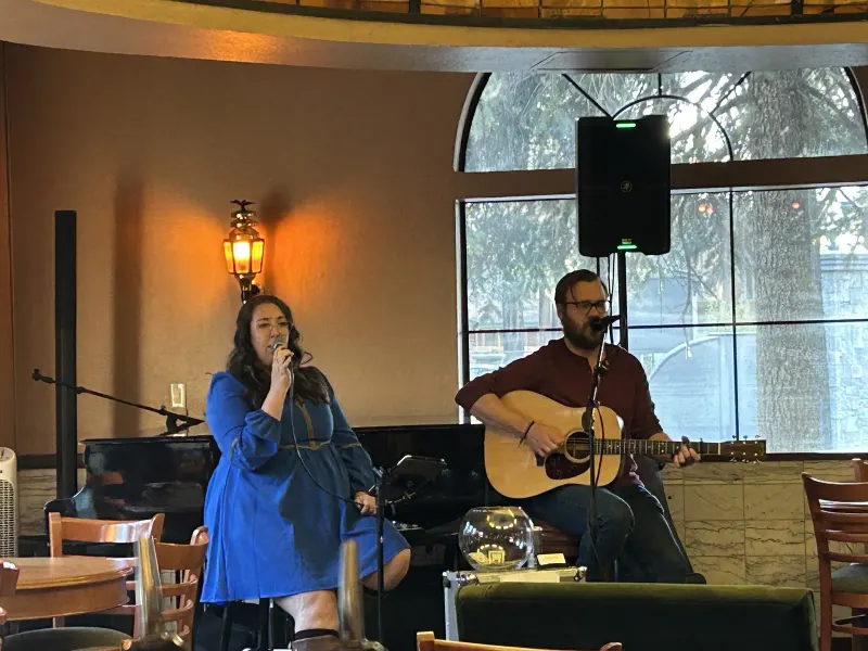 A singer and guitarist performing by the piano